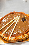 Ein köstlicher italienischer Kuchen mit glänzender Schokoladenglasur und eleganten weißen Schokoladenstiften - perfekt, um authentische italienische Backwaren zu präsentieren