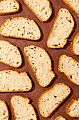 Top view of several slices of artisan bread arranged on a rustic wooden surface. The bread has a golden crust and an airy interior, ideal for culinary themes