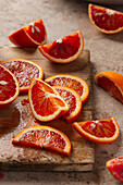 Slices of bright blood oranges, arranged on a weathered wooden board. The rich red tones and textured surface create an inviting presentation of the natural beauty of citrus fruits.