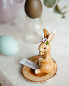 A charming Easter bunny figure decorated with delicate flowers sits next to naturally coloured eggs.