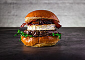 Delicious gourmet burger with crispy bacon, goat's cheese roll and caramelised onions, served on a fluffy brioche bun. Perfect for food lovers and culinary photographers.