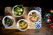 Gourmet bowls, chicken with glass noodles and peanuts, broccoli and cauliflower in satay sauce, tempura mushrooms in curry sauce and aubergine stew with rice