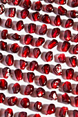 A collection of bright pomegranate seeds is carefully arranged on a clear white background. The rich red tones create a beautiful contrast that brings out their natural beauty and texture.