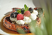 Enjoy this appetising snack with toast topped with raspberries, blackberries and blueberries A dollop of cream and a hint of mint enhance the flavour