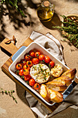 A delicious baked Camembert cheese, served with cherry tomatoes and crusty bread in a vintage bowl. Fresh thyme and roasted garlic add rustic charm to this gourmet appetiser.
