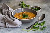 A classic beef stroganoff with tender slices of meat in a creamy sauce, garnished with fresh coriander. The dish is served with a bowl of chopped herbs
