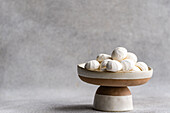Ein charmantes Arrangement von hausgemachten Mini-Zephyr-Marshmallows auf einer zweifarbigen Keramik-Sockelschale, die eine elegante und einladende minimalistische Präsentation ergibt