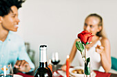 A romantic dinner with a red rose, candles and wine. A couple enjoys an intimate meal that creates a cosy and loving atmosphere, perfect for special occasions.