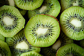 Frische Kiwi-Scheiben von oben mit ihrem leuchtend grünen Fruchtfleisch und den dunklen Kernen. Die Nahaufnahme hebt die saftige Textur und die natürliche Schönheit der Frucht hervor.