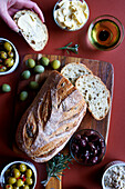 Selection of olive products, including Kalamata olive sourdough bread, green olive dip, olive oil, dairy-free olive spread, Sicilian olives and marinated green and black olives.