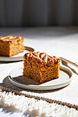 Pumpkin pie square with swirls of almond butter on a neutral background with golden forks