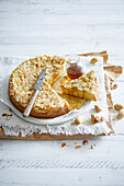 Sliced almond cake with flaked almonds, flavoured with brown vanilla sugar syrup on a white wooden base