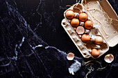 Fresh eggs in a carton on a black marble background. Horizontal alignment with negative space.