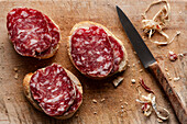 Slices of Italian salami on homemade bread on a wooden board