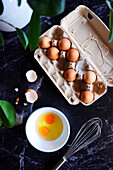 Fresh eggs in a carton while preparing food on a black marble background.