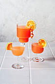 Blood orange margaritas on a tiled table with a grey background