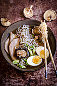Ramen noodles with chopsticks, surrounded by mushrooms
