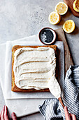 Applying the icing to a lemon and poppy seed cake
