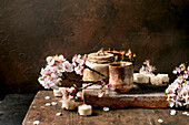Traditional Japanese tea ceremony with ceramic teapot, sweets, sesame cream and blooming cherry blossoms on a rustic stone platform. The dark, atmospheric setting creates an elegant atmosphere.