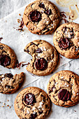 A selection of freshly baked chocolate biscuits, one of which has been bitten into and features melted chocolate and sea salt.