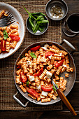 Fusilli with tomato sauce and mozzarella on a dark wooden background. Italian food. View from above. Copy area.