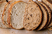 Closeup sliced fresh white bread and wholemeal bread with a crispy exterior and soft, airy texture on the inside, lined up on a wooden surface.