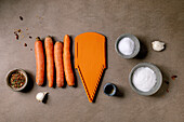 Korean and Asian cuisine. Ingredients for preparing a vegetable salad from marinated carrots. Raw carrots, spices, grater in a row. Mocha mousse colour background. Healthy cooking. Top view, room