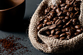 An open jute sack with a large quantity of coffee beans. Front view.