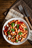 Fusilli with tomato sauce and mozzarella, on a wooden table. Italian food. View from above.
