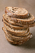 Close-up of freshly sliced sourdough bread, stacked on a brown background. Rustic, artisan bread with a crispy crust and airy texture.