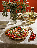 Freshly baked pizza with courgette crust, topped with cherry tomatoes, asparagus, spinach leaves and ricotta cheese.