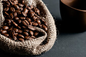 An open jute sack with a large quantity of coffee beans. Front view.
