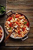 Fusilli with tomato sauce and mozzarella on a wooden table. Italian food. View from above. Copy area.