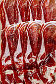 Thinly sliced Spanish Iberico ham Jamon Iberico paleta from the front leg of pork, close-up. View from above. Food background.