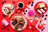 Pop art food, colour block aesthetics with double-layered, cream-filled cakes, cherries, macarons and strawberries.