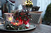 Weihnachtliche Deko auf Terrassentisch mit Scheinbeere, Windlicht aus Birkenrinde, Kränzchen und Wichtel