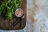 Wild mint with pink salt and herb scissors on a wooden board