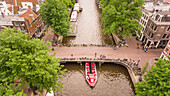 AMSTERDAM, THE NETHERLANDS - 7 July 2016 : Aerial view of a barge passing under a bridge on the canal in Amsterdam, The Netherlands.