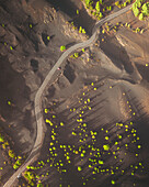 Aerial view of volcanic landscape with winding road and lush vegetation, El Paso, Spain.