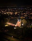 Aerial view of donia kerk illuminated at night amidst a tranquil cityscape, Makkum, Friesland, Netherlands.