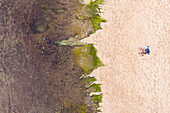 Aerial View Of a A couple laying on beach during low tide on Balangan beach in Bali, Indonesia.