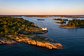 Aerial view of Pointe au Baril Lighthouse, islands, and forest with rocky shoreline at sunset, Georgian Bay, Canada.
