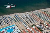 Tuscany, Italy - 16 July 2018: Aerial view of an AW 139 Agusta helicopter of the Italian Coast Guard flying over the beaches of Versilia during surveillance from above, Tuscany, Italy.
