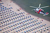 Tuscany, Italy - 16 July 2018: Aerial view of an AW 139 Agusta helicopter of the Italian Coast Guard flying over the beaches of Versilia during surveillance from above, Tuscany, Italy.