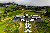 Aerial view of ermida de nossa senhora da paz church surrounded by lush greenery and tranquil hills, Vila Franca do Campo, Portugal.