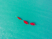 Aerial photography of empty red boats in the clear blue Lake Plastiras in Greece.