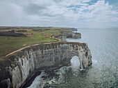 Aerial view of the majestic cliffs and rugged coastline with a natural arch, Etretat, France.