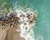 Luftaufnahme von Wellen, die an Felsen auf der Insel Santorin, Griechenland, brechen.