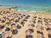 ACHAIA, GREECE - JULY 2018: Aerial view of vacationers on beach under straw parasols.