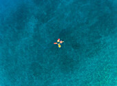 Aerial view of four friends floating on inflatable mattresses on Atokos island, Greece.